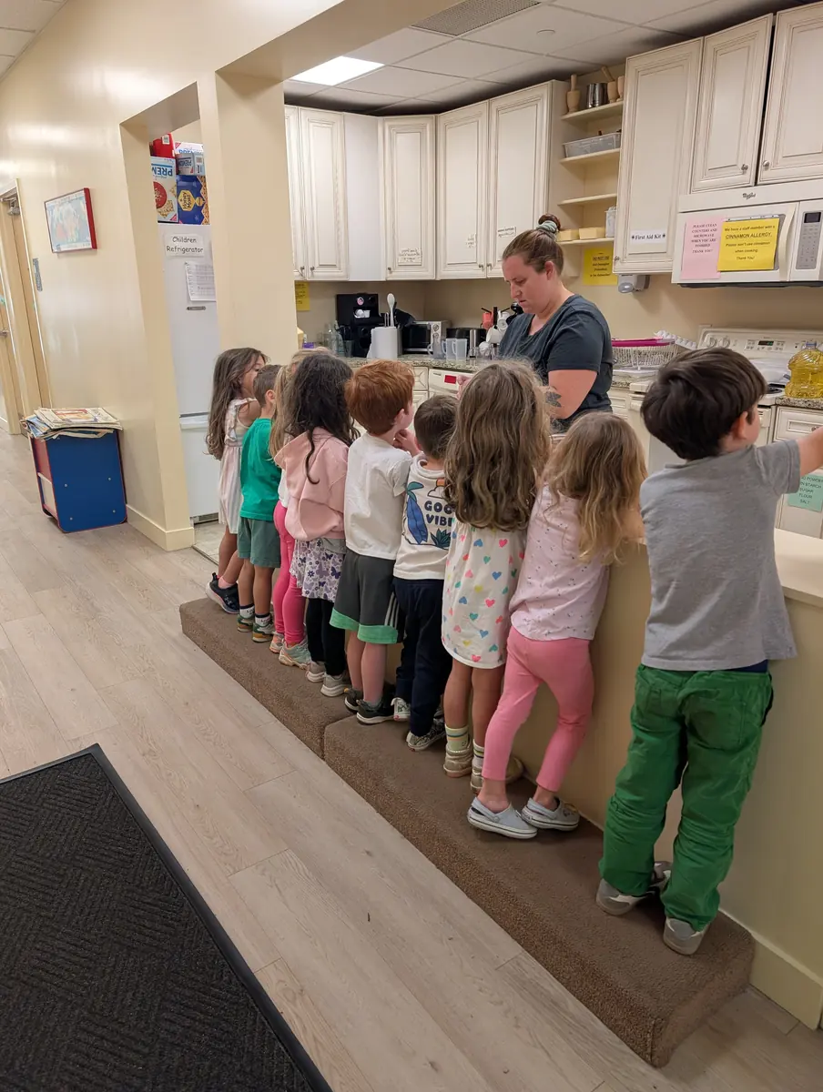 Preschoolers gathered around the kitchen counter for a hands-on cooking activity at Blossom Station