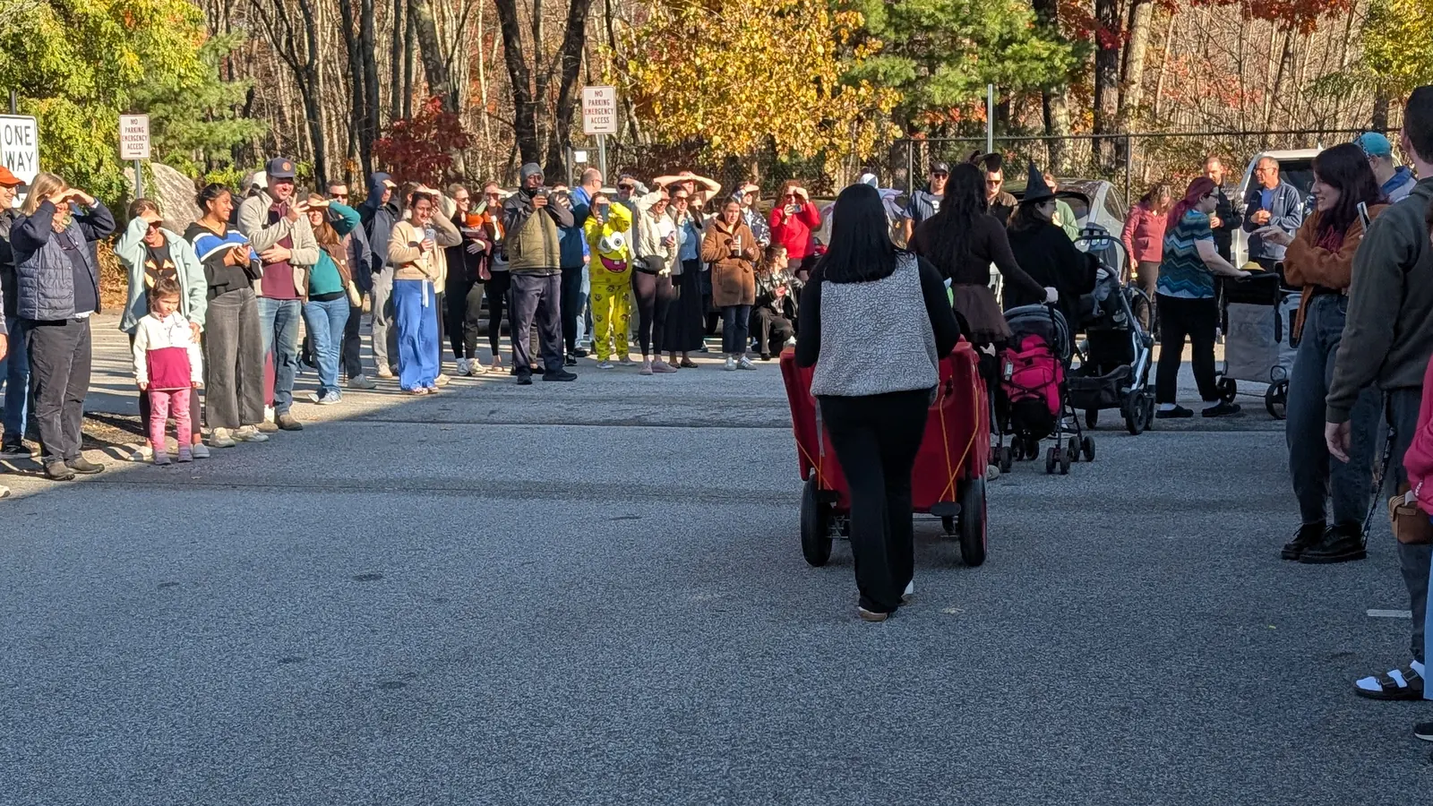 Families lining the Blossom Station parking lot under fall foliage as the 2026 Halloween Parade begins in Acton, MA