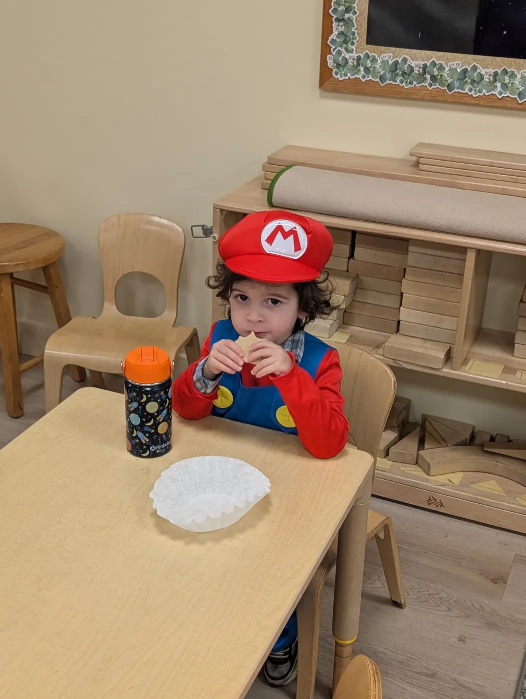 A toddler in a Mario cap and overalls enjoying a Halloween snack at Blossom Station