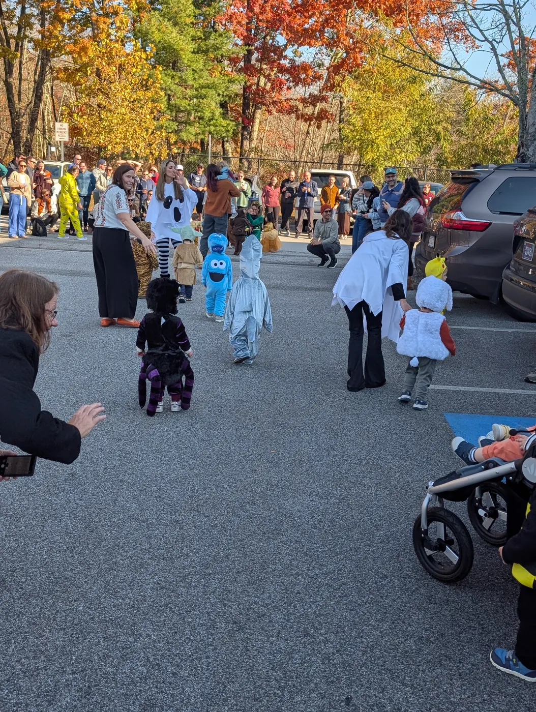 Families lining the Blossom Station parking lot as children in costume parade past