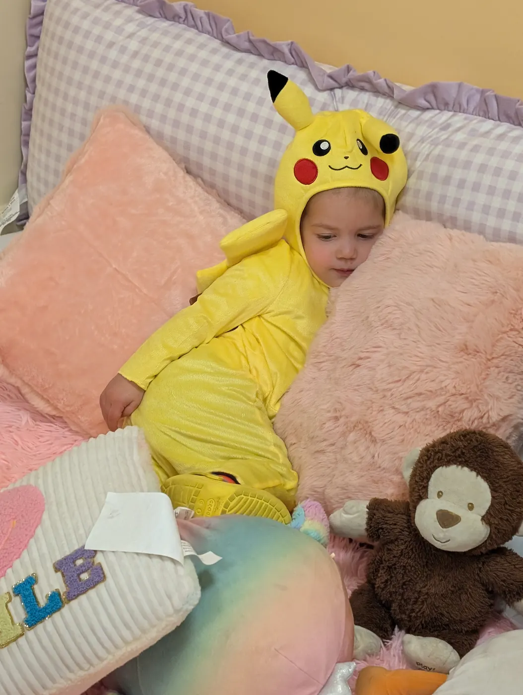 A toddler dressed as Pikachu resting on pillows in the Blossom Station reading corner