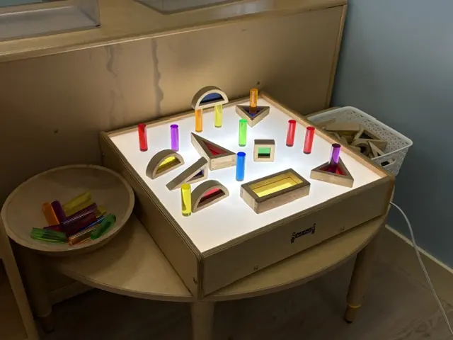 A light table with colorful learning materials at Blossom Station in Acton, MA