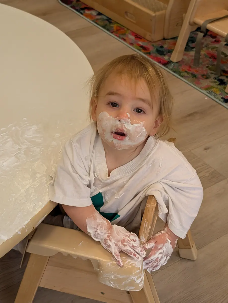 A toddler enjoying messy sensory play with shaving cream at Blossom Station