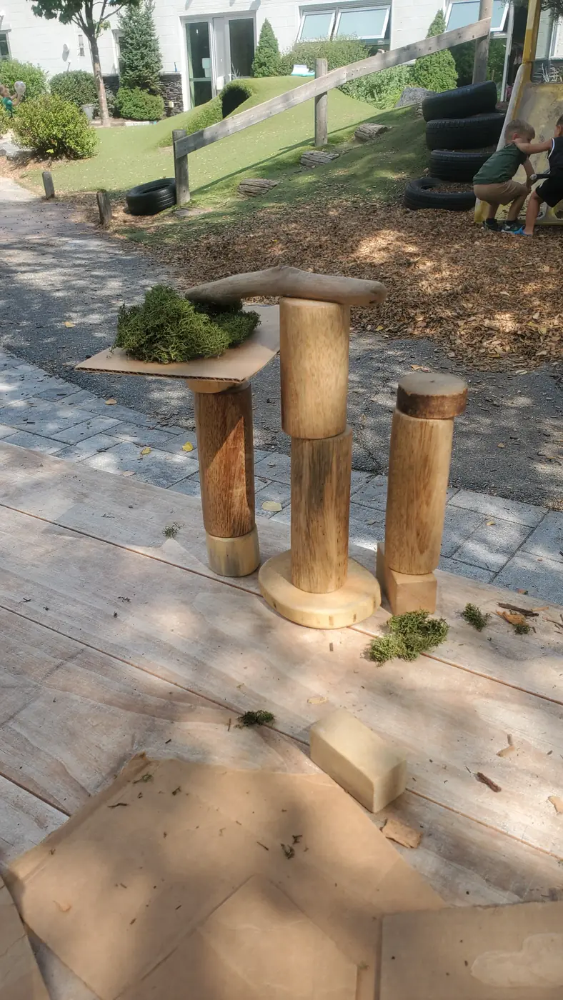 Natural wooden loose parts and moss set up for open-ended building on the TimberNook playground at Blossom Station